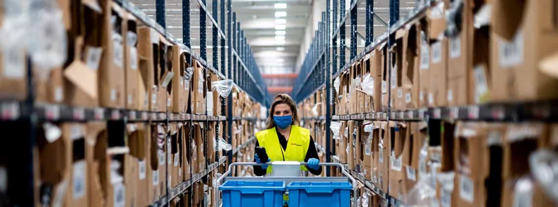 logistics professional pushes a cart through a warehouse 
